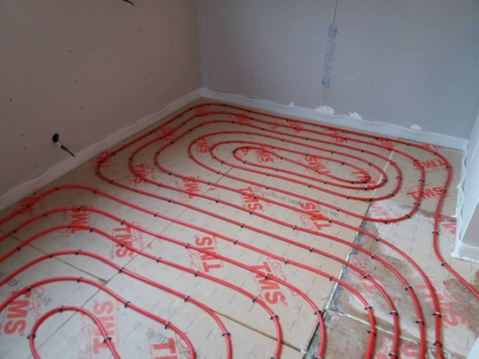 Chantier de construction intérieur avec installation de plancher chauffant hydraulique en cours