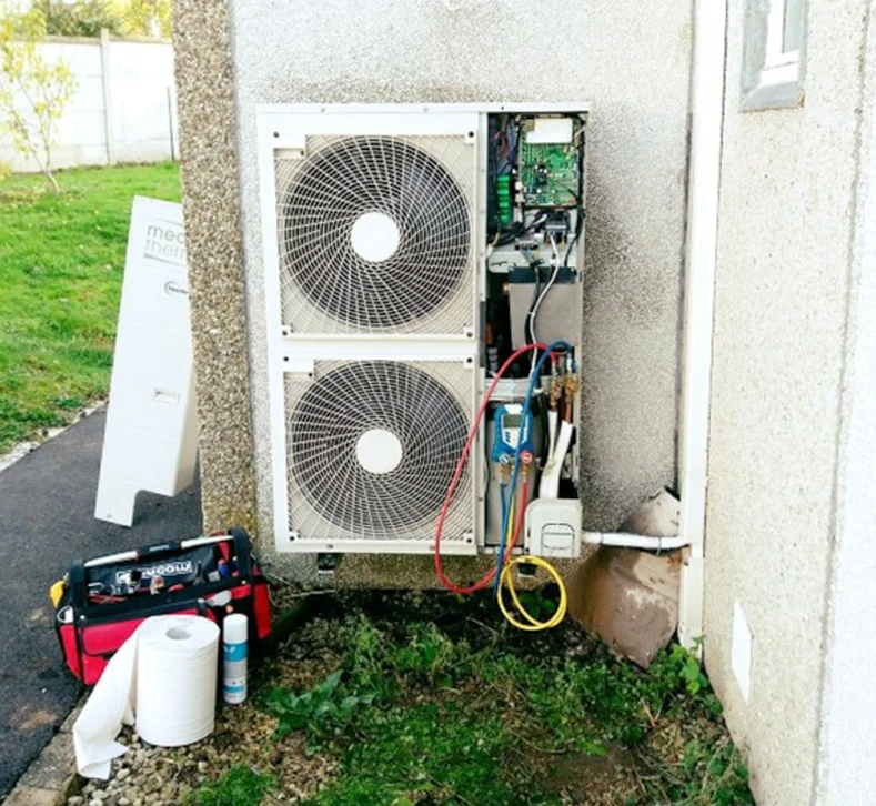 Atelier de réparation automobile avec mécaniciens en salopettes orange travaillant sur véhicules